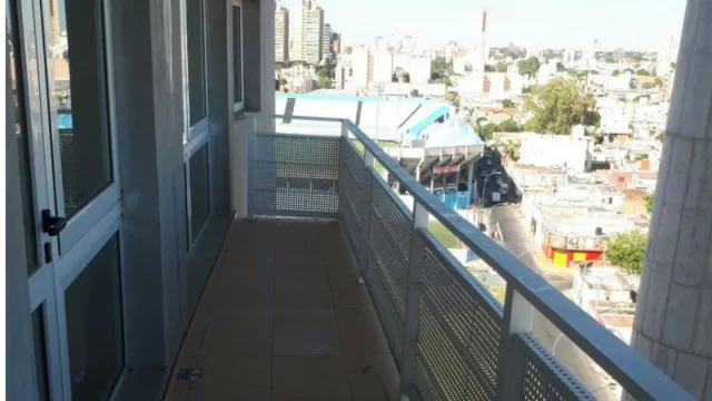El balcón de un departamento del 9no piso, contrafrente. Al fondo, la nueva tribuna de la cancha del Club Atlético Belgrano.