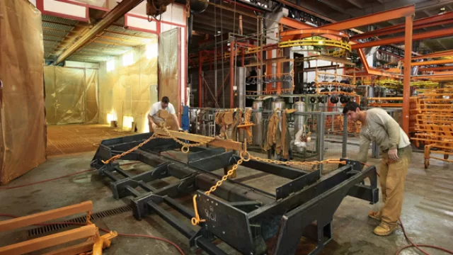 Dos operarios terminan de pintar parte de una de las sembradoras de Agrometal.