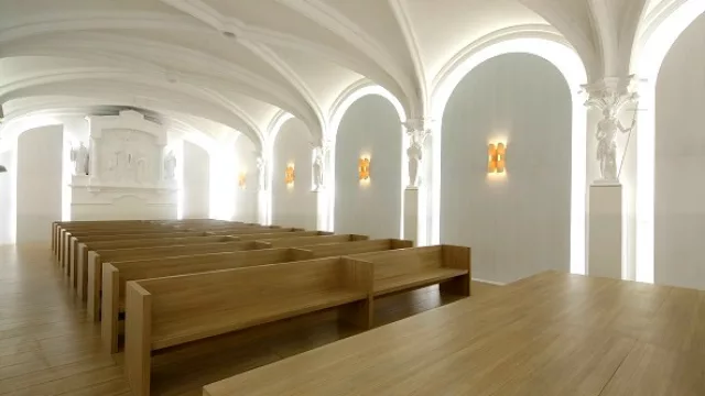 Líneas limpias de los asientos contrastan con las figuras y terminaciones de la capilla.