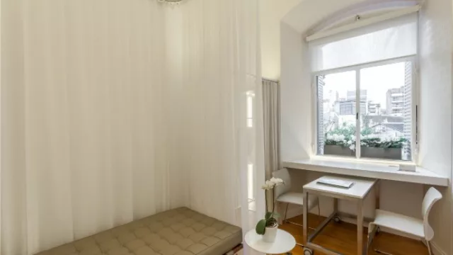 El sillón que a la vez juega de cama delimitado con cortinas y al lado del comedor/escritorio con luz natural.