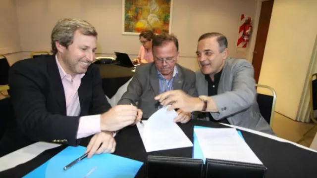 Rogelio Frigerio (n), en representación del Banco Ciudad y Luis Schenone y Felipe Lábaque, por Atenas, firman el convenio en una sala del Hotel Interplaza.