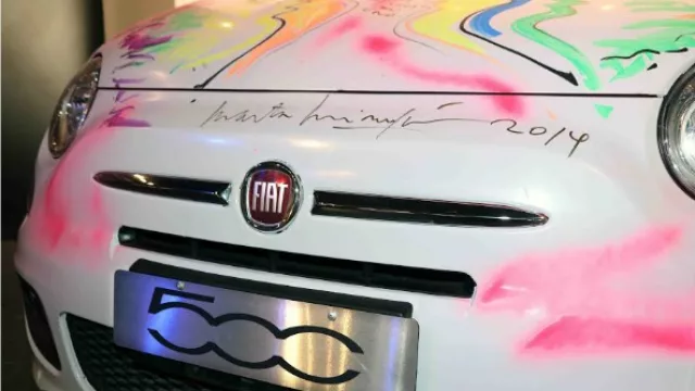 Sobre el inconfundible logo Fiat, la firma de la inconfundible artista Minujín.