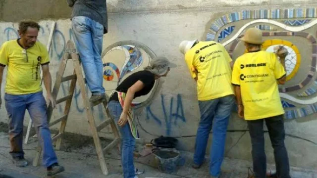 Los artistas trabajando y cubriendo graffiti con mosaicos. 