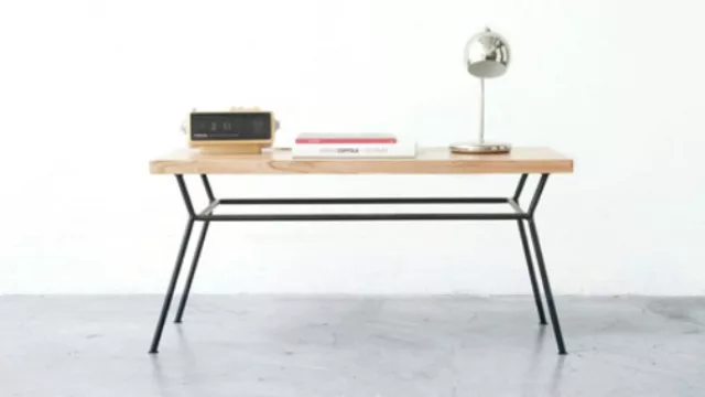 La mesa DOS se compone de una tabla de madera paraíso lacada con terminación mate y una base de hierro formada por líneas diagonales y horizontales.