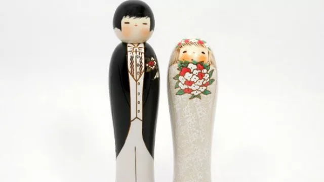 Los novios del pastel de bodas hechos Kokeshi. 