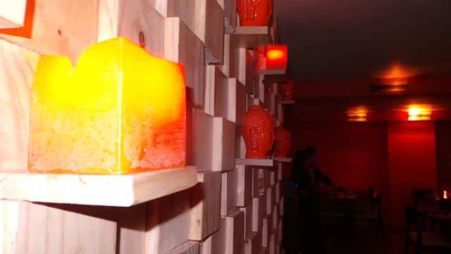 Paredes de madera, cabezas de Buda rojas y velas naranjas mantienen la calidez del ambiente.