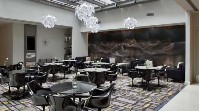 Toldos en las ventanas para controlar la radiación solar y asientos Saarinen en el restaurante.