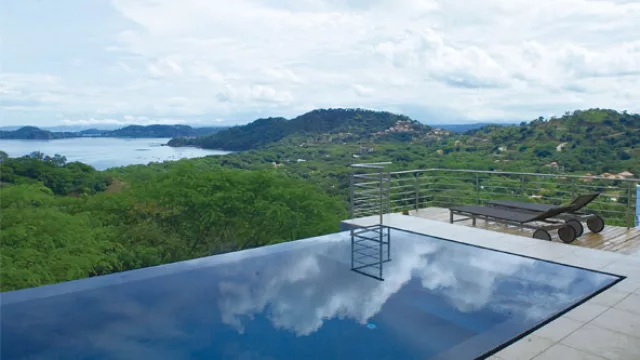 La piscina con borde infinito está servida de un solado de deck y baldosas atérmicas.