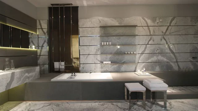 Una tarima de mármol  contiene la bañera y continúa a manera de banco dentro de la ducha.