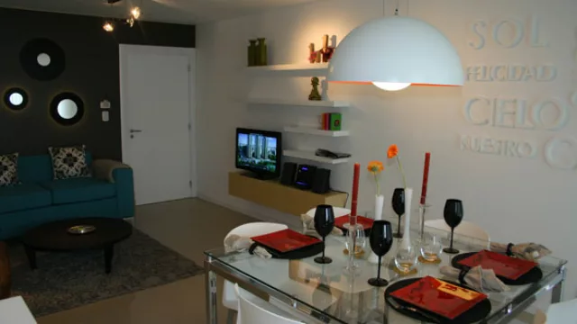 Alto Panorama en Córdoba. El mueble de TV y la biblioteca, diseños de las interioristas, complementan las superficies laqueadas blancas con la madera clara.