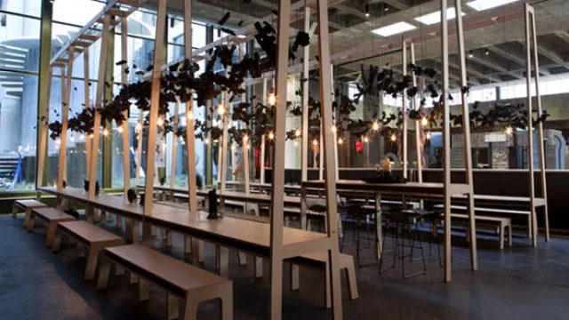 El espacio recrea los grandes comedores de las antiguas fábricas de principios de siglo 20, reinterpretados a partir de una visión contemporánea y ambivalente.